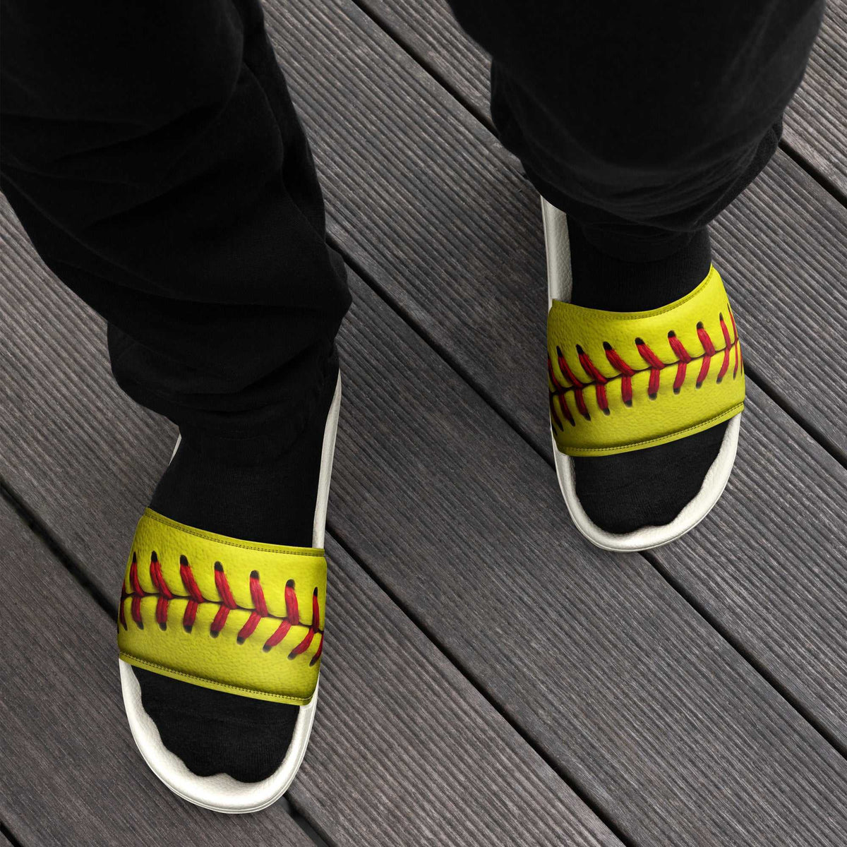 Men’s slides with bright yellow faux leather straps printed with red softball stitching and white contoured soles.